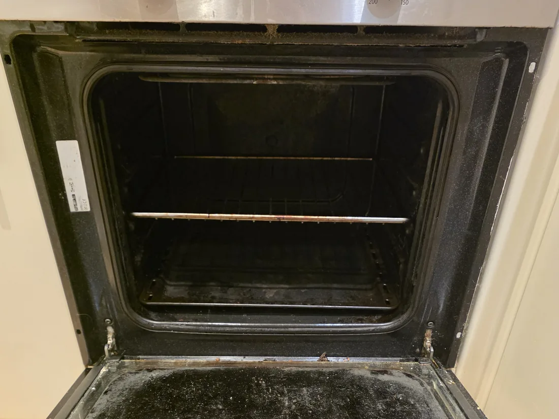 Built-in oven before cleaning, with grease across the door glass and cavity