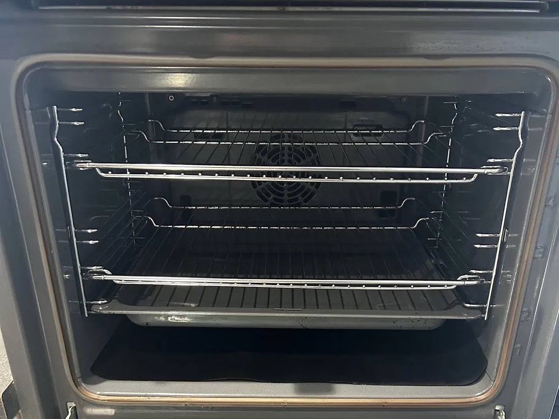 Fan oven interior after cleaning, with clean shelf runners, racks and fan cover