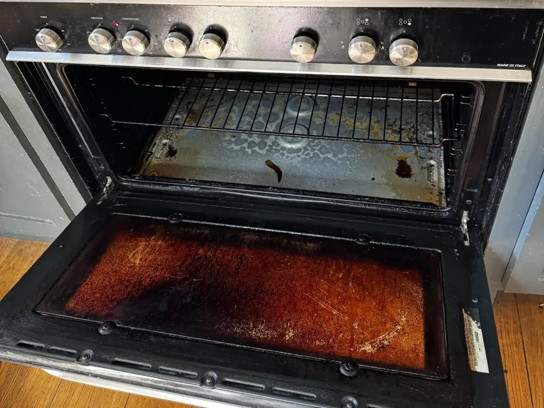 Gas range cooker before cleaning, with grease on the hob and burnt-on residue in the oven