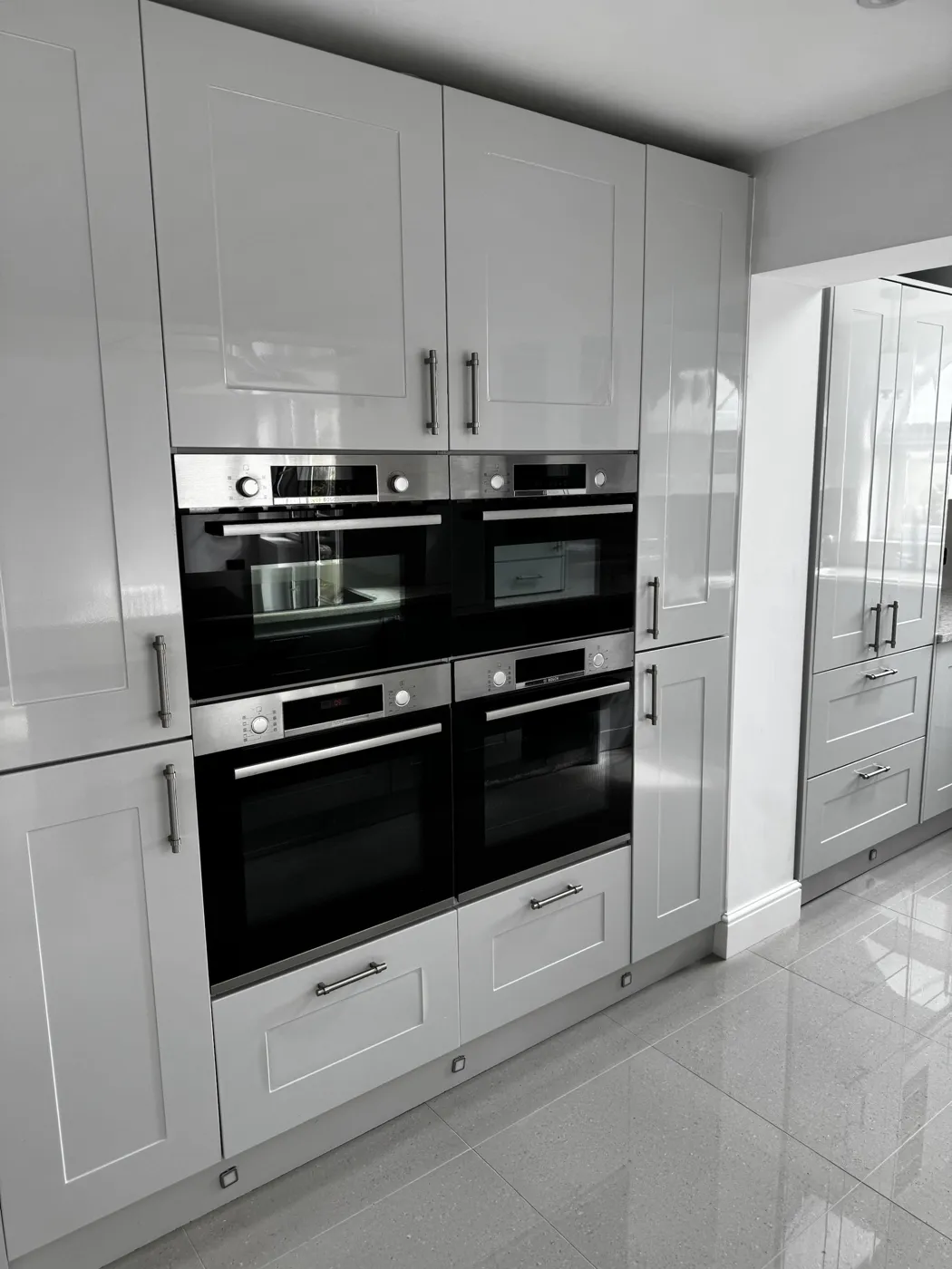 Clean kitchen with built-in ovens and glossy units